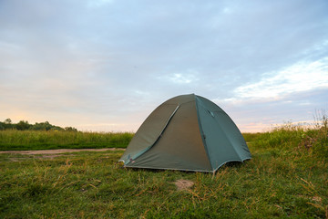 tourist tent on the high bank of the river at sunset