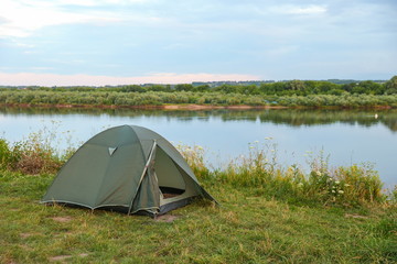 tourist tent on the high bank of the river at sunset
