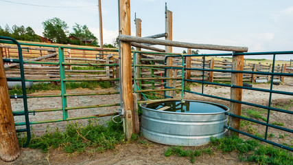 Stock tank and metal fence panels and wooden fencing in the animal corral on a working ranch near...