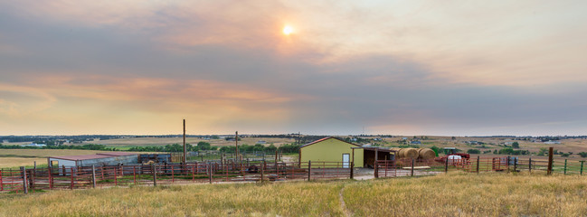 Obraz premium Pastoral scene at sunset on a working ranch near Denver with barn, large round hay bales, sheds, corrals, metal and wood fencing
