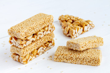 Peanut and Sesame Brittle bars (Indian Peanut Chikki) on white wooden background.