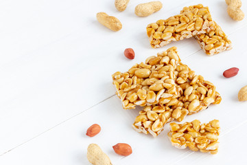 Plate of peanut brittle candy pieces on a white wooden background.