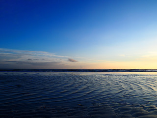 Fototapeta na wymiar Calm ocean tides at dusk. Blue hour solitude.