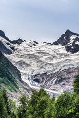 Beautiful landscape of glacier in summer season. Glacier mountain with green vegetation on high ground in cloudy weather.