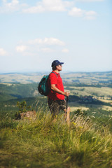  Active man with backpack hiking in  mountain forest in the summer, selective focus