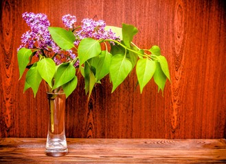 Branch of blooming lilac on a brown wooden background
