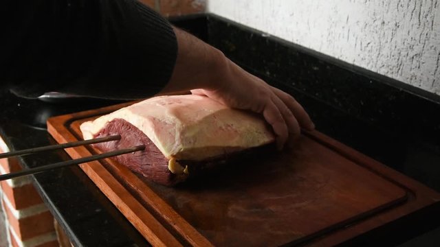 Espetando uma picanha para colocar na churrasqueira, tradicional churrasco do sul do Brasil feito em casa.
