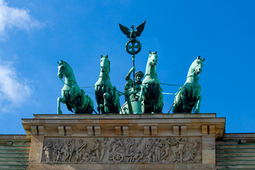 A close up view of the quadriga that stands on top of the iconic Brandenburg gate in Berlin. The statue features a goddess (Victoria) driving a four horse chariot while holding Prussian eagle standard © Grandbrothers