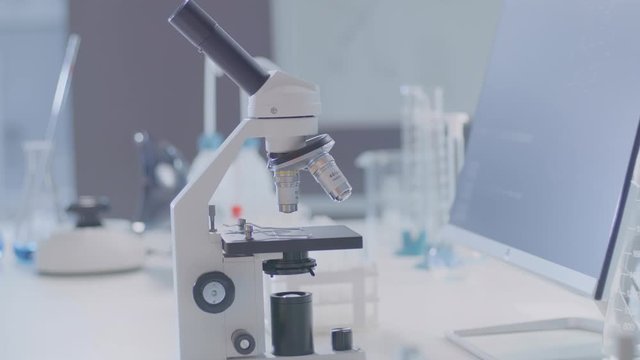 A dolly shot of the microscope in the modern lab.