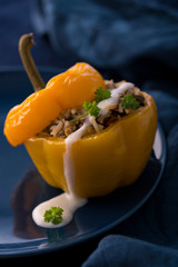 Colorful baked bell peppers stuffed with mince and rice on blue background