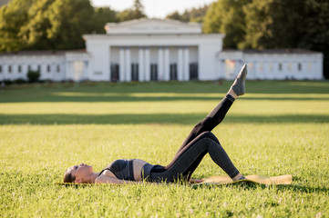 Fototapeta premium Beautiful young woman lying on a yellow mattress doing pilates or yoga, one leg stretch beginner exercises