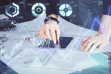 Double exposure of man's hands holding and using a digital device and forex graph drawing. Financial market concept.
