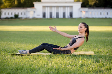 Fototapeta premium Beautiful young woman lying on a yellow mattress doing pilates or yoga, roll up intermediate exercises
