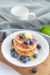 A healthy breakfast of pancakes, berries, butter, and honey