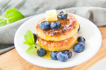 A healthy breakfast of pancakes, berries, butter, and honey