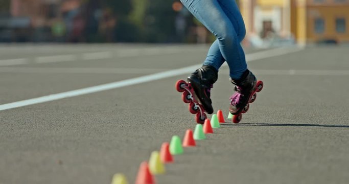 Legs of an athlete in roller skates go around the cones, freestyle butterfly. Professional freestyle in roller skates, cones are in a row. 4k, 10bit, ProRes