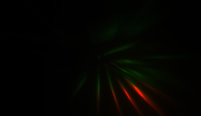 Light particles in motion, creating a burst of glowing multicolored rays on a black background. Energetic glow lights wallpaper.