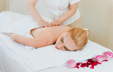 Beautiful woman lying on the bed for a spa asia massage at luxury spa and relaxation. The masseuse is massaging her back and shoulders in the spa room.