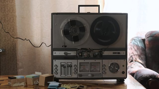 Old reel-to-reel tape recorder plays tape. Retro concept of turntable reel to reel tape recorder. Old vintage grandma's or grandfather's room with old music playing.