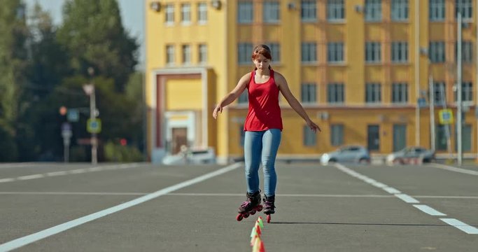 Pretty girl athlete makes rotations around herself on roller skates and goes around the cones, professional roller sports. Roller skating training outdoors. 4k, 10bit, ProRes