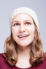 Fototapeta premium Teenage Ideas. Closeup Portrait of Positive Caucasian Teenager Girl Wearing Teeth Brackets. Posing Against Gray.