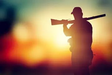 Foto op Canvas Male hunter silhouette with a gun at sunset © BillionPhotos.com