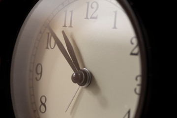 Fototapeta na wymiar Closeup of Traditional Alarm Clock With Black Arrows. Against Black Background