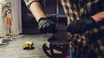 Ski maintenence. Removing excess wax from race ski base plastic scraper. Ski service and repair. Winter shop worker doing base repair. Rental workshop service. Repairman In Workshop Ski Service