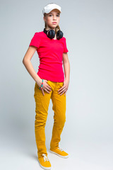 Fototapeta premium Youth Lifestyle. Full Length Portrait of Caucasian Teenager Girl with Wireless Headphones. Standing Over Gray background.