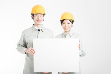 メッセージボードを持つ作業服を着た男女