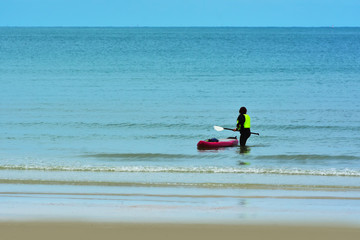 Fototapeta na wymiar On the beach a man rowing on the sea.
