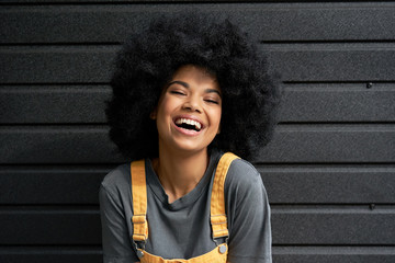 Happy stylish African American teen girl wearing yellow trendy sundress with Afro hair looking at...