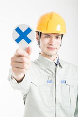 バツのプラカードを持った男性作業員