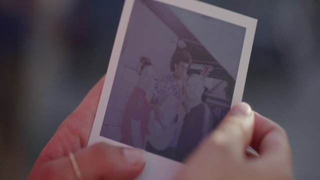 Woman Holds Polaroid Picture of Friends in Slow Motion, Close Up