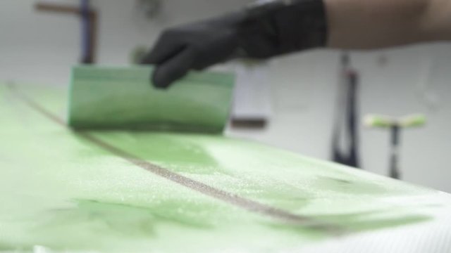 surfboard being glassed and painted slow motion using squeegee