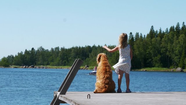Cute young girl and dog welcoming boat guests in idyllic Stockholm archipelago