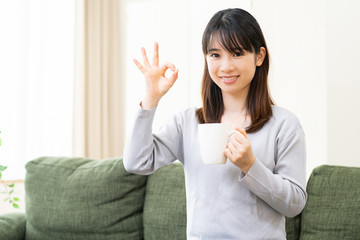 リビングのソファでコーヒーを飲む女性