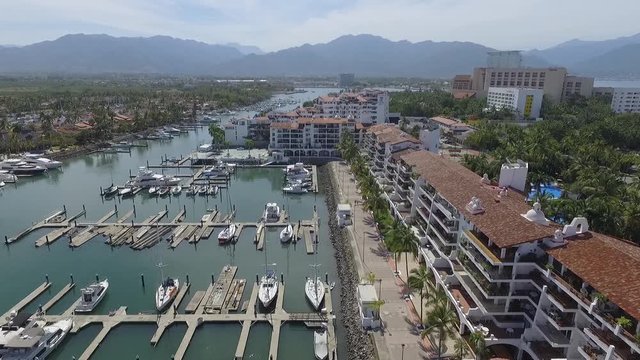 Detalle de los yates atracados en la marina de Puerto Vallarta, Jalisco, el drone ascendiendo lentamente para descubrir la zona residencial