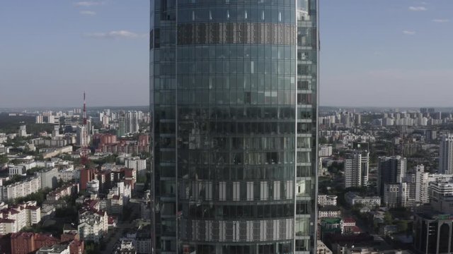 Aerial view of Vysotsky skyscraper in Ekaterinburg city in Russia. Stock footage. Flying towards the glass facade tall building on modern cityscape background, concept of architecture.