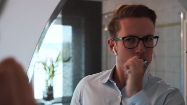 Close up shot of a young caucasian man washing his teeth very hard in front of a mirror