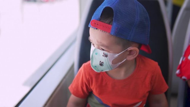 Little boy on a moving train in a hat and a face mask against coronavirus pandemic. New normality situation Going outside after lockdown with protective gear. Face mask for children