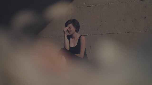 Young woman in an evening dress crying in the dark