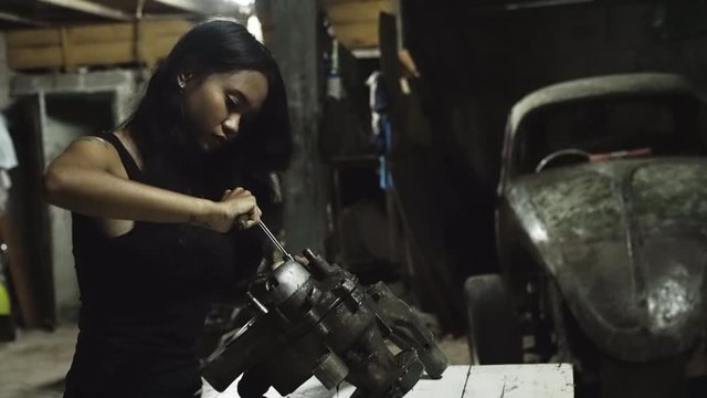 A young Asian female mechanic working in an automotive garage.
