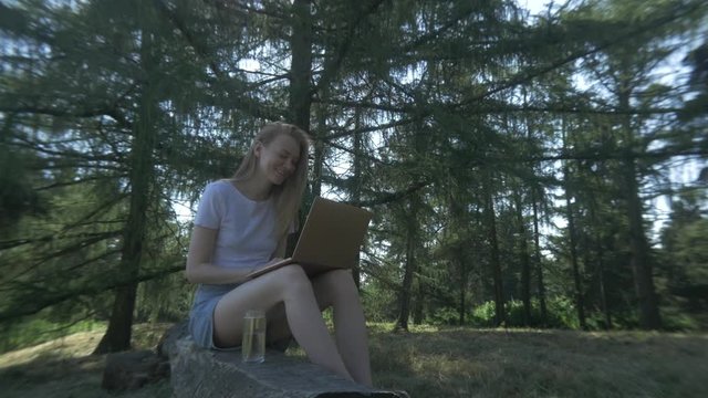 A Pretty Girl Communicates Remotely Online In The Morning Park. Skype Conversation, Web Talk.