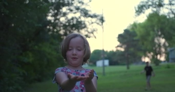 Portrait View Of Sweet Young Innocent Caucasian Girl Standing In Backyard And Releases Lightning Bug And Gets Scared, Close Up Handheld Pan Slow Motion