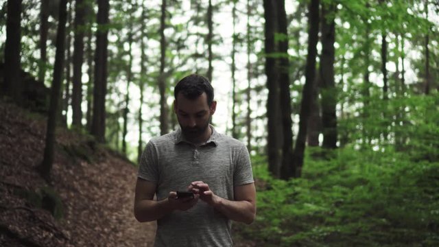 Caucasian man lost in forest using mobile phone with no reception, trying to find way out