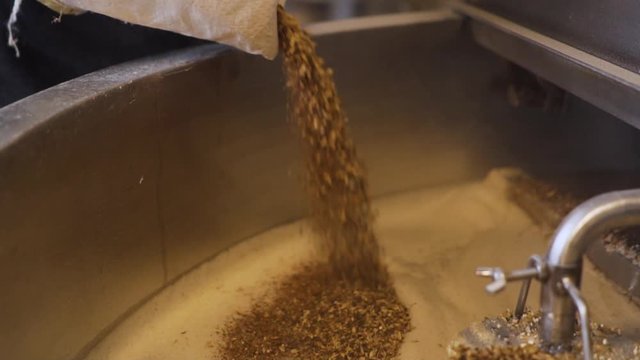 man throwing malt into a brewery pot, close up slowmo