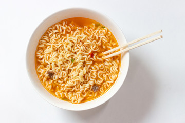 A plate with ready ramen and wooden sticks on white background, view from above