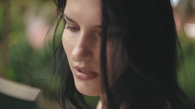 Pretty young brunette feeling hot outdoors and fanning with a notebook. Brunette woman waving and cooling up on a hot day