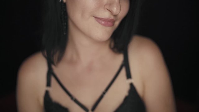 Close up of a pretty brunette woman doing a kissing gesture and smiling on black background